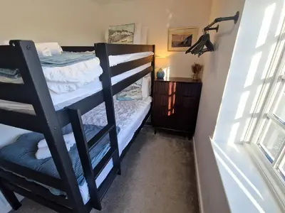 a bedroom with bunk beds in a room with a window at Great location very spacious. Sea and castle view in Marazion