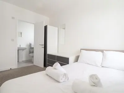 two white beds in a room with a bathroom at 1 Queensway Gardens in Hayle