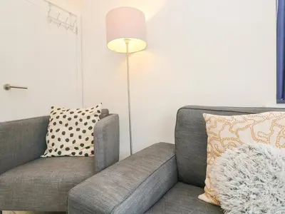 a living room with a gray couch and a lamp at 1 Queensway Gardens in Hayle