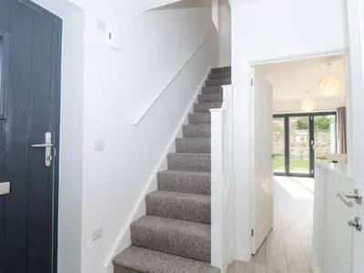 a staircase in a home with white walls and a hallway at 1 Queensway Gardens in Hayle