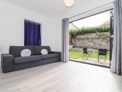 a living room with a couch and a sliding glass door at 1 Queensway Gardens in Hayle