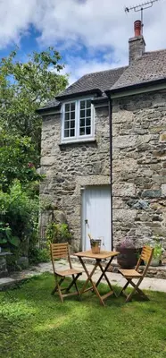 a table and two chairs in front of a house at The Little Chapel Annexe in Helston