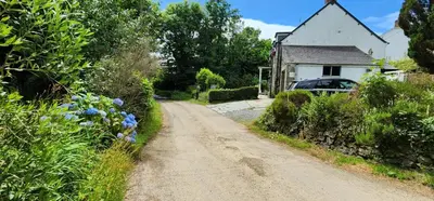 a dirt road in front of a house with a car at The Little Chapel Annexe in Helston