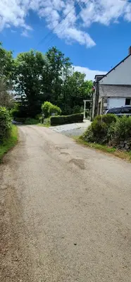 a dirt road next to a building and trees at The Little Chapel Annexe in Helston