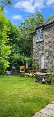 a picnic table and bench in front of a stone building at The Little Chapel Annexe in Helston