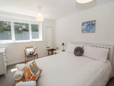 a bedroom with a white bed and a chair at Sea Holly in St Ives