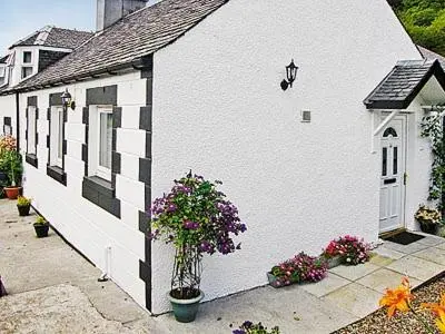 a white building with flowers on the side of it at The Old Store in St Merryn