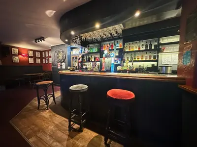 a bar with two stools in front of a counter at The Western in St Ives