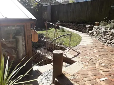 a garden with a brick walkway and a guitar at Bright cosy house, garden, central to town & beach in Falmouth