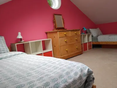 a bedroom with a bed and a dresser with a mirror at Bright cosy house, garden, central to town & beach in Falmouth