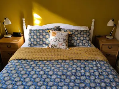 a bed with a blue and white comforter and two lamps at Bright cosy house, garden, central to town & beach in Falmouth