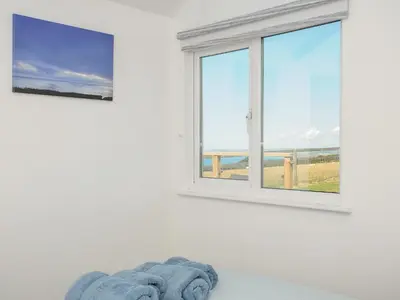 a white room with a window and blue towels at Lundy View Chalet in Bude