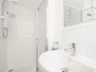 a white bathroom with a sink and a shower at Lundy View Chalet in Bude