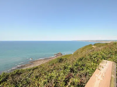 a bench on a hill next to the ocean at Lundy View Chalet in Bude