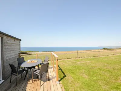 a patio with a table and chairs on a deck at Lundy View Chalet in Bude