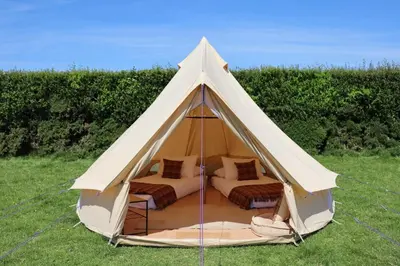 a white tent with two beds in a field at Rescorla Retreats- Poldark in Mevagissey