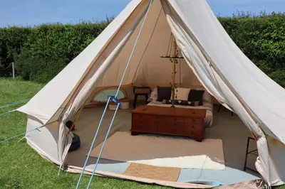 a canvas tent with a bed in a field at Rescorla Retreats- Poldark in Mevagissey