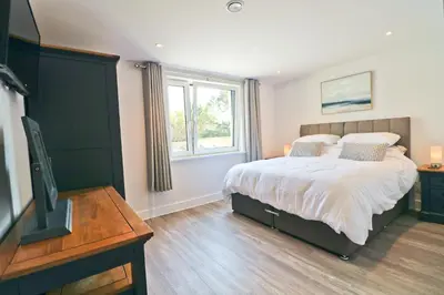 a bedroom with a bed and a flat screen tv at Sea view apartment, first floor in St Merryn
