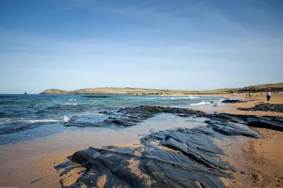 a beach with some rocks in the sand and water at Sea view apartment, first floor in St Merryn