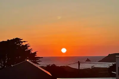 a sunset over the ocean with the sun in the sky at Sea view apartment, first floor in St Merryn