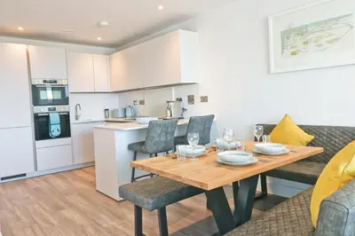 a kitchen and dining room with a wooden table and chairs at Sea view apartment, first floor in St Merryn