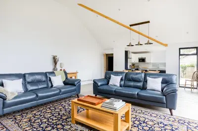 a living room with two blue couches and a table at The Garden House in Wadebridge