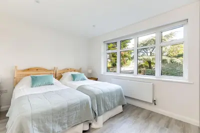 two beds in a white room with windows at The Garden House in Wadebridge