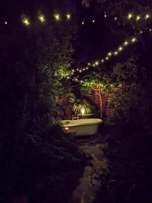 a bath tub in a garden at night with lights at The Applehay in Constantine