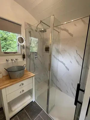 a bathroom with a glass shower with a sink at Gillan Creek Retreat in Helston