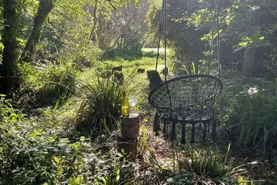 a swing in the middle of a garden at Gillan Creek Retreat in Helston