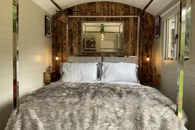 a bedroom with a large bed with a mirror at Gillan Creek Retreat in Helston