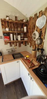 a kitchen with white cabinets and wooden counter tops at Gillan Creek Retreat in Helston