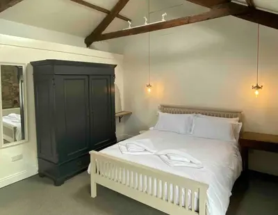 a bedroom with a white bed and a black cabinet at Foundry cottage in Hayle