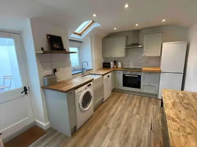 a kitchen with a washer and a white refrigerator at Foundry cottage in Hayle