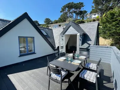 a patio with a table and chairs on a deck at Crow's Nest, Polperro in Polperro