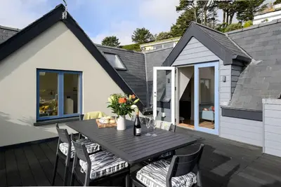 a table and chairs on a deck with a house at Crow's Nest, Polperro in Polperro