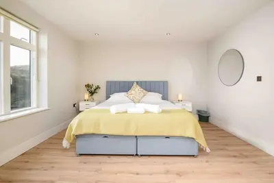 a white bedroom with a bed with a yellow blanket at Crow's Nest, Polperro in Polperro