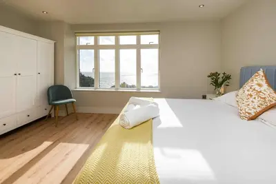 a bedroom with a large white bed and a window at Crow's Nest, Polperro in Polperro
