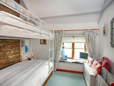 a bedroom with two bunk beds and a desk at Railway Cottage in Camelford