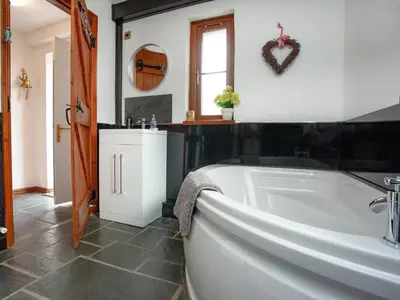 a bathroom with a bath tub and a sink at Railway Cottage in Camelford