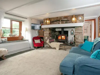 a living room with a blue couch and a fireplace at Railway Cottage in Camelford