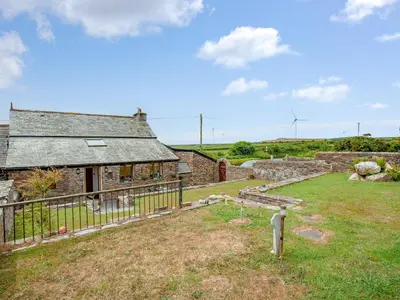 an old stone house with a fence and a yard at Railway Cottage in Camelford