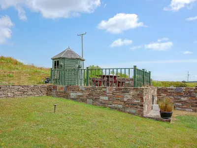 a brick retaining wall with a building in a yard at Railway Cottage in Camelford