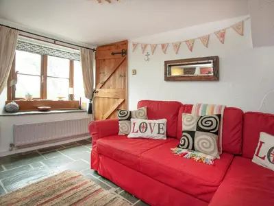 a red couch in a living room with a red at Railway Cottage in Camelford