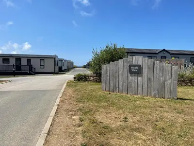 a fence with a sign on it next to a road at Holiday Home with Stunning Views in Newquay
