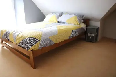 a bedroom with a bed with a yellow and white comforter at Beach Side Top Floor Property, Balcony & Sea Views in Newquay