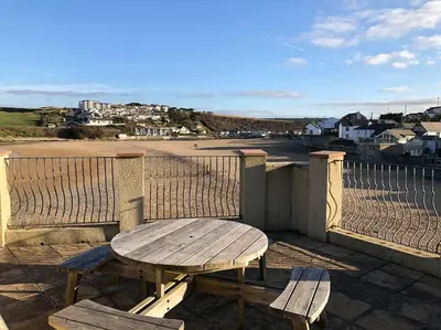 a picnic table and two benches on a balcony overlooking a beach at Beach Side Top Floor Property, Balcony & Sea Views in Newquay