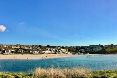 a beach with a group of people in the water at Beach Side Top Floor Property, Balcony & Sea Views in Newquay