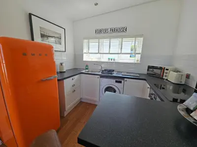 a kitchen with an orange refrigerator and a sink at Ocean Swell (49) in Bude