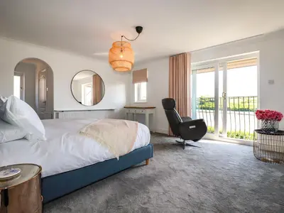 a bedroom with a bed and a chair and a mirror at Newquay Tamarisk Lodge on the Gannel in Newquay